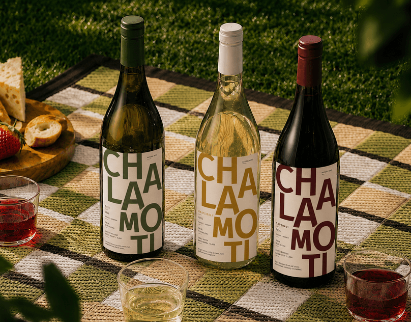 Three CHALAMOTI wine bottles on a woven picnic blanket